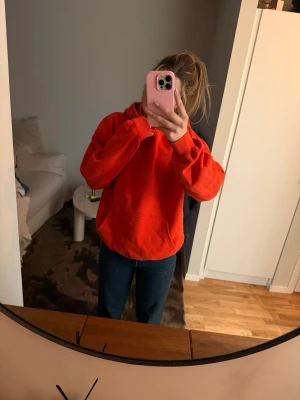 Röd hoodie med huva och magficka - Röd hoodie med stor huva. Hoodien har en avslappnad passform och är gjord i mjukt material. Inga synliga loggor eller tryck, enkel och clean design som passar till det mesta.