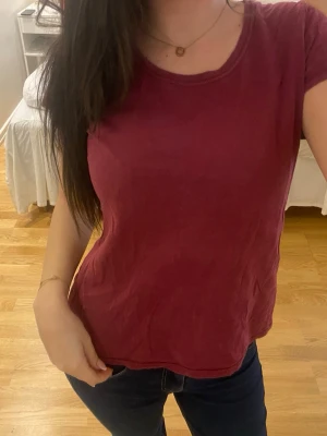 Mörkröd basic t-shirt - En enkel och stilren mörkröd t-shirt med rund halsringning och korta ärmar. Perfekt till jeans eller shorts för en avslappnad look. T-shirten är i mjuk bomull och har en normal passform.