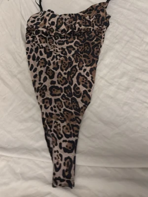 Leopardmönstrad baddräkt med smala band - Snygg baddräkt med leopardmönster i brunt, beige och svart. Modellen har smala axelband och en åtsittande passform som framhäver figuren. Perfekt för dig som vill sticka ut på stranden eller vid poolen.