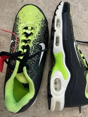 Nike Air Max sneakers svart/neongul - Nike Air Max sneakers i svart och neongul med vit sula och synliga luftbubblor. Skorna har en cool färgövergång med stänk-effekt, vita swoosh-loggor på sidorna och svarta snören. Ovandelen är i textil och syntet, insidan är neongul för extra pop.