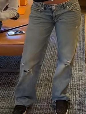 Ljusblåa baggy jeans med slitningar - Baggy jeans i ljusblå denim med slitna detaljer på båda benen. Klassisk femficksmodell med låg midja och raka ben. Perfekta för en avslappnad streetstil. 