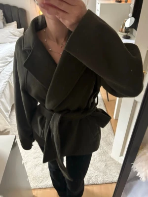 Mörkgrön kappa med knytning - Mörkgrön kappa från gina. Säljs inte längre. Modellen är kort och har ett snöre i midjan, fin både knuten och ej. Skriv vid funderingar, pris kan diskuteras 💞