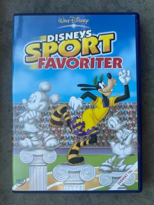 Disneys sportfavoriter DVD - DVD-film med Disneys Sportfavoriter. Filmen innehåller flera sportrelaterade kortfilmer med Disney-karaktärer som Långben, Musse Pigg och Pluto. Textning: Svenska, Finska, Danska, Norska, Engelska, Estniska. Speltid: 76 minuter. Produktionsår: 2005.  Finns på språk: Svenska, Finska, Danska, Norska, Engelska    OBS!! skivorna är begagnade så det kan förekomma repor/hairlines på skivorna, men då jag kollar igenom alla filmer jag säljer garanterar jag att alla funkar felfritt om inget annat står! :