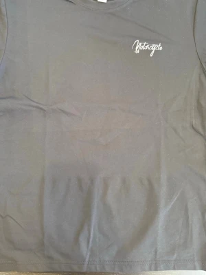 Svart t-shirt med motorcykeltryck - Cool svart t-shirt med tryck av en motorcyklist och texten 'Motorcycle' på bröstet. Stort motiv på ryggen med motorcykel och inspirerande citat. Perfekt för dig som gillar streetstyle och motorcyklar. Klassisk passform och rund hals.