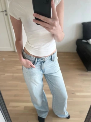 Ljusblåa vida jeans med låg midja - Säljer ett par ljusblåa jeans med låg midja och raka, vida ben. Jeansen har klassisk femficksdesign och är tillverkade i denim. Storlek 34/36