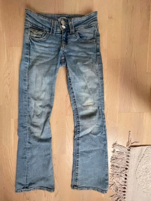 Blå bootcut jeans - Säljer ett par blå bootcut jeans dubbelknappar vid midjan.