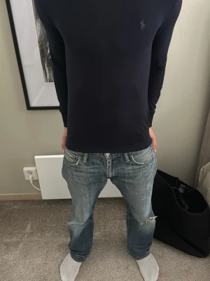 Mörkblå tröja från Ralph Lauren - Snygg mörkblå långärmad tröja från Ralph Lauren med diskret broderad logga på bröstet. Tröjan har en slim fit-passform och är tillverkad i ett mjukt, tunt material som sitter skönt på kroppen. Perfekt för dig som gillar stilrena och klassiska plagg. Kan passa XS