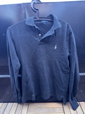 Svart långärmad skjorta från Polo Ralph Lauren🙌🤩 - Klassisk svart långärmad skjorta från Polo Ralph Lauren med vit broderad logga på bröstet. Skjortan har krage, knappar vid halsen och är tillverkad i mjuk bomull. Perfekt för en avslappnad men ändå stilren look. Är en M men passar S🙌🤩