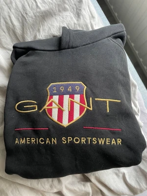 Svart Gant hoodie i fint skick - Säljer en svart hoodie från märket Gant, använd fåtal gånger. Storlek S/176 cm