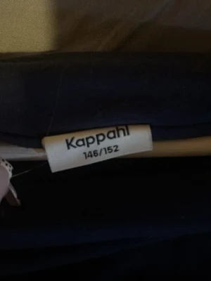 Svart offshoulder topp från Kappahl - En svart offshoulder topp från Kappahl i mjukt material. Toppen är ärmlös och har en stilren, enkel design som passar perfekt till jeans eller kjol. Snygg och bekväm för dig som gillar minimalistisk stil.