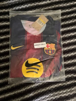 FC Barcelona matchtröja Nike - Säljer en officiell FC Barcelona matchtröja från Nike med klubbmärke och sponsorlogga på bröstet. Tröjan har klassiska blå och vinröda ränder samt gul Nike-logga. Perfekt för dig som älskar fotboll och vill visa ditt stöd för Barca.
