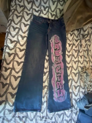 Blå low rise jeans från JADED london - Unika blå low rise jeans från JADED london med rosa hjärtan på bakfickorna! Raka ben och cool streetwear-vibe, perfekta för dig som vill sticka ut.
