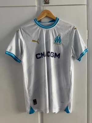 Marseille matchtröja - Snygg vit matchtröja från Puma för Olympique de Marseille. Snygg tröja att ha till i sommar. Storlek L men passar M. Tröjan är bara testad aldrig använd. Priset är såklart inte hugget i sten