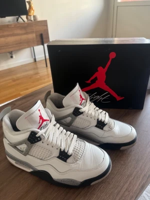 Air Jordan 4 Retro 'White Cement' - Hej! Säljer ett par Air Jordan 4 Retro ‘White Cement’ i mycket fint skick, cirka 8.5/10. Skorna är väl omhändertagna och fortfarande väldigt fräscha både utvändigt och invändigt. Ett riktigt clean och eftertraktat par som passar till allt. Storlek 41 och jag säljer dem för 2 000 kr. Kvitto finns och skorna är köpta från Soleplus, så skorna är självklart äkta. Perfekt för både användning och samling. Hör gärna av dig vid frågor eller intresse!