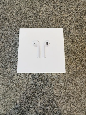 Apple AirPods trådlösa hörlurar - Säljer ett par vita Apple AirPods med laddningsetui. Snygg och stilren design i plast, perfekt för dig som vill ha trådlös frihet och bra ljud till mobilen eller datorn. Kommer i originalförpackning. Lite repor på laddningsetui, inget som på värkar ljudet.