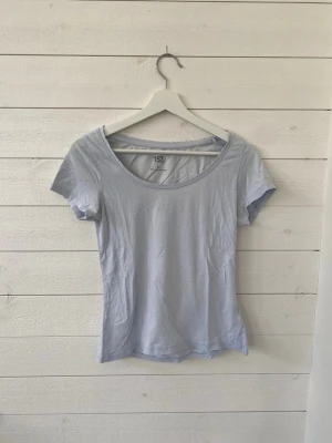 Ljusblå t-shirt från 157 - En basic ljusblå t-shirt från 157 med rund halsringning och korta ärmar. Tillverkad i mjuk bomull och har en slim passform som sitter snyggt på kroppen. Perfekt att matcha med jeans eller kjol. Den har lite defekter, pris kan diskuteras.