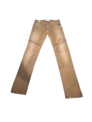 Beige slim fit jeans med slitningar - Säljer ett par beige slim fit jeans med coola slitningar och patch-detaljer på framsidan. Jeansen har klassisk femficksdesign och raka ben. Perfekta för dig som gillar en streetwear-inspirerad look.