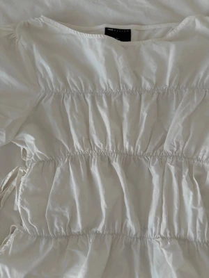Vit volangblus från asos - En söt vit blus från asos med volangdetaljer och avslappnad passform.  Blusen har rynkade partier och är perfekt för en fräsch och stilren look. Lätt och luftig i materialet, passar bra till varmare dagar.
