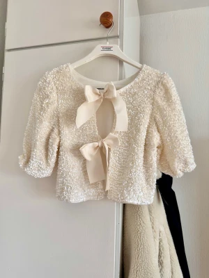 Glittrig topp med rosetter och paljetter - In color cream. Unused