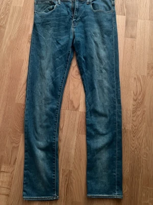 Levi's blå raka jeans - Klassiska blå jeans från Levi's med raka ben och femficksdesign. Jeansen har en snygg tvättad look och tydliga sömmar på bakfickorna. Tillverkade i bomull med en autentisk denimkänsla. Perfekta för en avslappnad och stilren vardagsstil.
