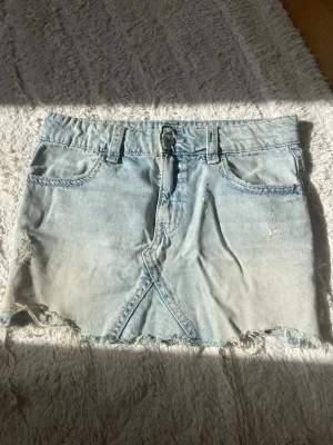 Ljusblå jeanskjol med slitningar - Supersöt ljusblå jeanskjol från Gina Tricot!! Sömmarna är rosafärgade och bakfickorna har fina broderade mönster med matchande rosa färg som sömmarna💕💕perfekt nu till våren och sommaren 