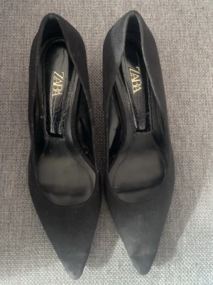 Svarta pumps med glittrig klack Zara - Snygga svarta pumps från Zara med spetsig tå och låg, smal klack i guldglittrigt material. Skorna har en elegant och stilren design, perfekta för att lyfta vilken outfit som helst. Materialet ser ut att vara mockaimitation. Kan tänka mig att sänka priset vill bara bli av med dom och tjäna pengar, är fattig student😃😃