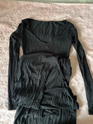 Svart långklänning - Mysigt svart långklänning som är långärmad har en djup v-ringning och är gjort i ett mjukt, stretchigt material som passar perfekt.