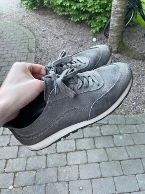 Massimo Dutti Trainers - Snygga grå sneakers i mocka från Massimo Dutti med vita sulor och svarta yttersulor med grovt mönster. Klassisk låg modell med snörning och stilren design som passar till det mesta. Perfekta för dig som gillar en clean och tidlös look.