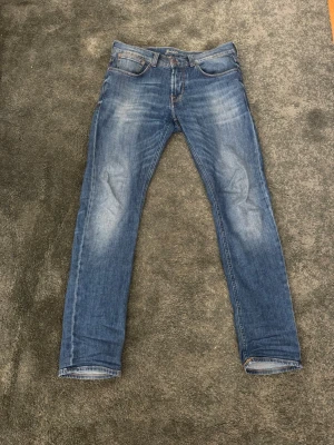 Blå raka jeans från Baldessarini - Snygga blå jeans från Baldessarini med raka ben och klassisk femficksdesign. Jeansen har en lätt tvättad look med slitningar på låren och knäna samt patch med logga bak i midjan. Perfekta för en avslappnad stil. Storlek 31 (Italiensk kvalitet)