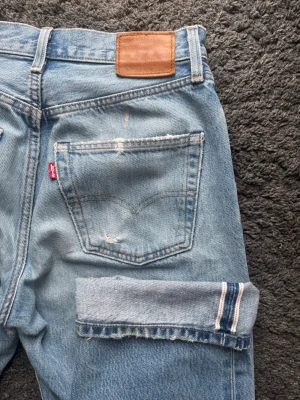Selvedge Levis 501 90s Jeans - Selvedge Levis Jeans.  Färg: Ljusblå | Modell: 501 90s | Storlek: W30 L28 på lappen men sitter mer som en L30 enligt mig. kolla måtten nedan! | Lagade i grenen och en lite slitna där, alla slitningar/defekter visas på bilderna | Premium Levis Vintage Selvedge Jeans  Mått: Midja: 37,5 cm Längd: 98,5 cm Beslut: 20 cm Lår från grenen: 28 cm  Tveka inte att höra av dig minsta fråga eller fundering!  Skickas snabbt!