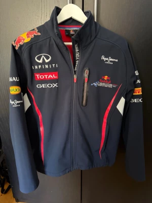 Red Bull Racing jacka  - Mörkblå Red Bull Racing formel 1 jacka i storlek small, allmänt använd med lite defekt på redbull logan på axeln som syns på bilden. Annars helt felfri.
