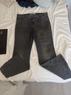 Grå bootcut jeans med utsvängda ben - Säljer ett par gråa bootcut jeans med utsvängda ben och klassisk femficksdesign. Jeansen har en snygg tvättad look och normal midja. Perfekta för dig som gillar en avslappnad men trendig stil.