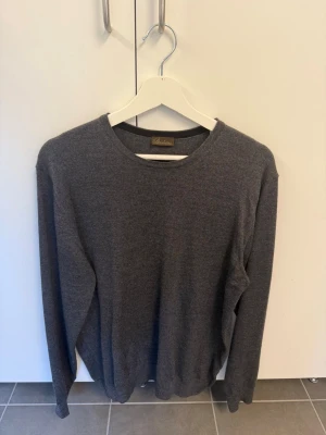 Mörkgrå tröja från Stenströms i 100% Merinoull, stl L - Mörkgrå stickad tröja från Stenströms i storlek L. Tröjan har rund halsringning, långa ärmar och en klassisk, stilren design. Perfekt för lager-på-lager och enkel att matcha med olika outfits.
