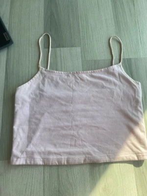 Ljusrosa cropped linne med smala band - Säljer ett ljusrosa cropped linne med tunna axelband. Enkel och stilren design, perfekt till sommaren eller som lager på lager-plagg. Mjukt material som känns skönt mot huden. I storlek xxs men passar även xs