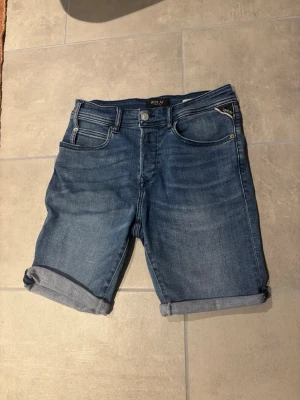 Blå jeansshorts från Replay - Snygga blå jeansshorts från Replay med klassisk femficksdesign och uppvikta benslut. Shortsen har normal passform och är tillverkade i bomull för en bekväm känsla. 