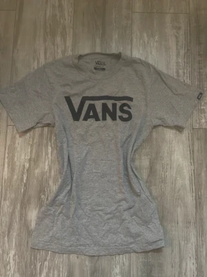 Grå Vans t-shirt - Säljer en grå t-shirt från Vans i klassisk passform med stor svart Vans-logga på bröstet. Storlek Xs, använd 1 gång💓