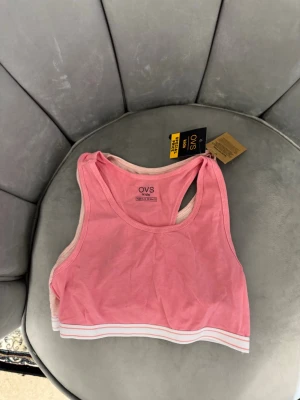 2-pack rosa sportiga toppar OVS - Säljer ett 2-pack sportiga toppar från OVS i olika rosa nyanser. Båda har breda axelband och vit resår med rosa rand längst ner. Perfekta som bekväma underkläder eller till träning. Materialet är mjukt och stretchigt för skön passform.
