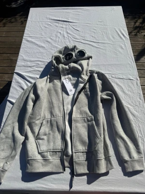 Grå hoodie med glasögon från C.P. Company - Snygg hoodie i storlek L, passar även M. Tveka inte att skriva för fler bilder eller om du undrar något//Felkannn