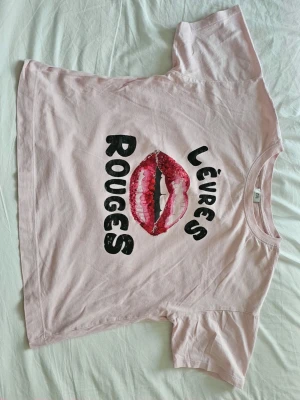 River Island Lèvres Rouges t-shirt i 100% bomull – Stl M 💋 - supercoola ljusrosa t-shirt från River Island med tryck av röda läppar i gnistrande paljetter! Den har en skön, lite rymligare passform. Materialet är 100% bomull och plagget är i mycket bra skick (alla paljetter är intakta) 💋Mått:Hellängd: 55 cmFrån armhåla och ner: 30 cmBredd (armhåla till armhåla): 56 cmStorlek: Medium (M)