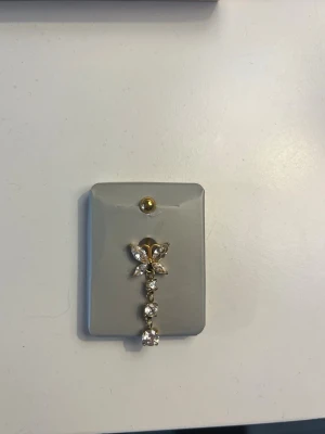 Guldig navelpiercing  - Jättefin navelpidrcing i kirurgiskt stål som aldrig är använd eller testad. Säljer då jag köpte fel färg.  Staven är 10 mm lång och 1,6 mm bred. 💕