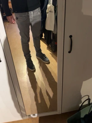 Gråa slim fit jeans herr - Säljer ett par gråa slim fit jeans med klassisk femficksdesign och dragkedjegylf. Jeansen har smal passform och sitter tajt längs benen. Perfekta för dig som gillar en modern och stilren look.