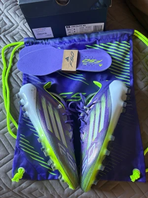 Adidas F50 Elite AG fotbollsskor lila - Säljer ett par Adidas F50 Elite AG fotbollsskor i lila med neon- och vita detaljer. Skorna har en modern, strömlinjeformad design och levereras med matchande skopåse och extra innersula. Perfekta för spel på konstgräs och tillverkade i syntetmaterial för lätt känsla. (Använda 3 träningar) Nypris 3099 kr