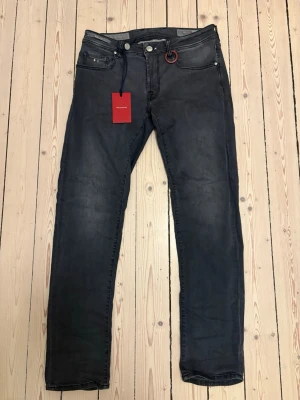 Tramarossa jeans - Snygga svarta slim fit jeans från Dsquared2 med klassisk femficksmodell och diskreta slitningar. Jeansen har en röd logotypdetalj vid linningen och en röd patch bak i midjan. Tillverkade i mjuk denim med stretch för extra komfort.