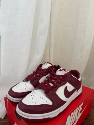 Nike dunk low retro - Säljer dessa dunksen med röd sula, stilrena och snygga! Har en liten slitning på insida tyg bak i hälen som visas på bilden också. Annars i fint skick⭐️