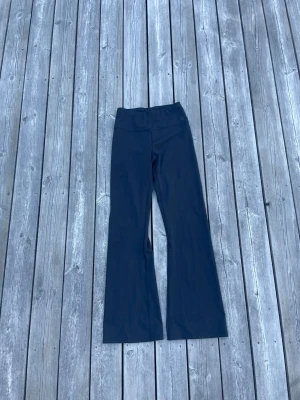 Svarta bootcut tränings tights - Säljer ett par svarta tränings tights med bootcut-modell och hög midja. De är stretchiga och sitter bekvämt. 