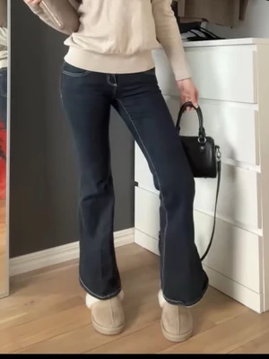 Mörkblå bootcut jeans med kontrastsömmar - Snygga mörkblå bootcut jeans med vita kontrastsömmar och ultra low midja från gina tricot. Dem är i petite 