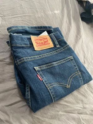 Levi's 511 - Säljer ett par klassiska blå Levi's 511or. Jeansen har tydliga kontrastsömmar, två bakfickor och den ikoniska Levi's-lappen på linningen. Materialet är slitstark denim och modellen har en cool vintagekänsla. Storlek 164cm, passar W28-W29 och L30