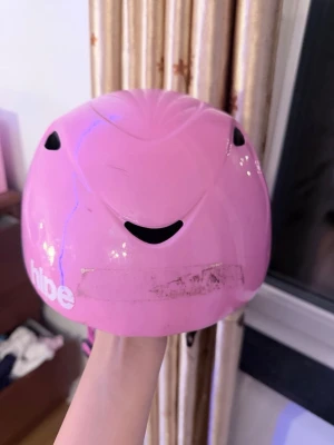Rosa hjälm från hibe - Säljer en rosa hjälm från hibe med svart ventilationsdetalj och justerbart spänne baktill.det är lite smutsigt där framme från tejpen, men det kommer jag ta bort innan jag fraktar! Den är mjuk inuti så det är inte hård för barn.