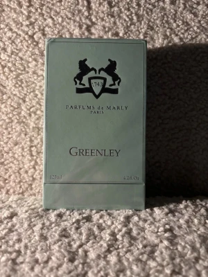 Parfums de Marly Greenley 125ml oöppnad  - Greenley från Parfums de Marly är en exklusiv parfym i en stilren, ljusgrön kartong med silverdetaljer och logotyp med två hästar. Flaskan rymmer 125 ml och doften är Eau de Parfum. Märket är känt för sina lyxiga och eleganta dofter inspirerade av 1700-talets Frankrike.