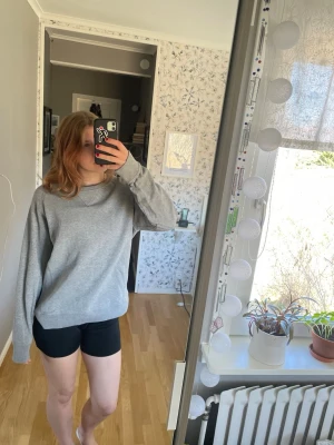 Grå långärmad tröja i bomull - En enkel och stilren grå långärmad tröja i mjukt bomullsmaterial. Tröjan har en avslappnad passform och rund halsringning utan synliga knappar eller detaljer. 